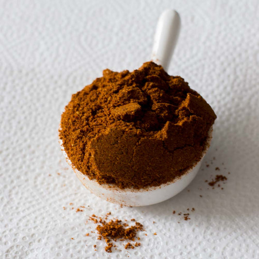 Rich and aromatic Chicken Masala powder served in a white ceramic spoon, handcrafted by Athithi Gruha Foods.